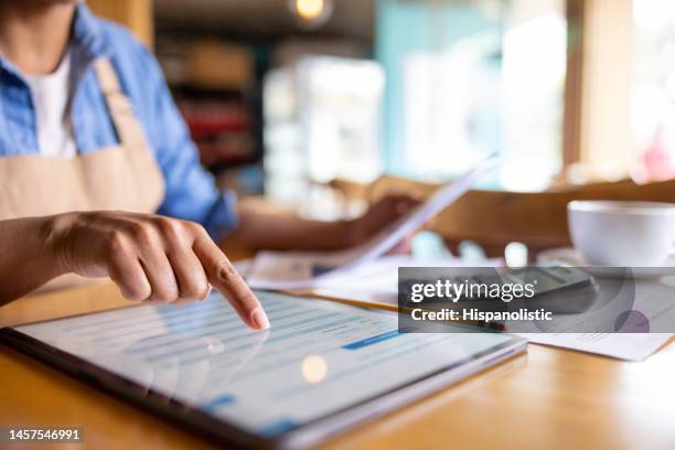 dueño de un negocio haciendo la contabilidad en una cafetería - accountancy fotografías e imágenes de stock