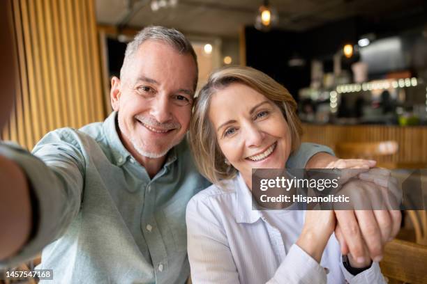 seniorenpaar macht ein selfie in einem café und lächelt in die kamera - mature cafe happy stock-fotos und bilder