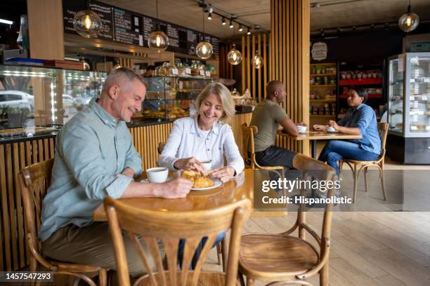 happy couple having a cup of coffee at a cafe - coffee shop couple stock pictures, royalty-free photos & images