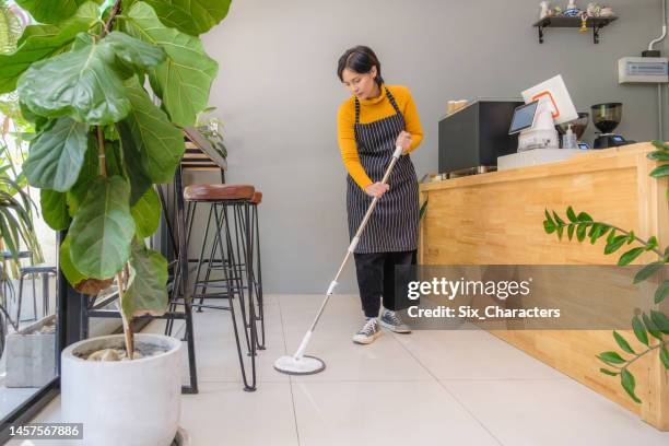 young asian woman worker or coffee shop owner cleaning floor with mop at coffee shop cafe - restaurant cleaning stock pictures, royalty-free photos & images