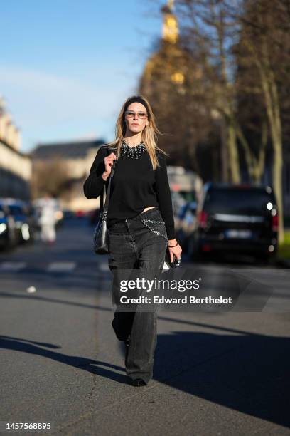 Natalia Verza wears a black large headband, glasses, a black wool with embroidered large black pearls fringed collar from Givenchy, a black shiny...