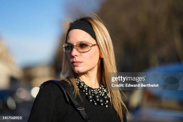 Natalia Verza wears a black large headband, glasses, a black wool with embroidered large black pearls fringed collar from Givenchy, outside Givenchy,...