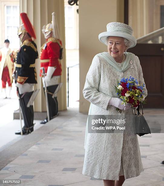 Queen Elizabeth II holds a bouquet of flowers as she arrives at Buckingham Palace at the end of a carriage procession following a national service of...