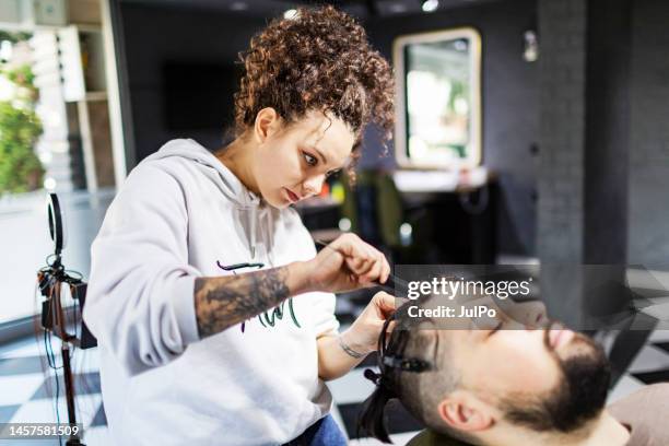 young female hairdresser braiding hair to client at barber shop - hair type stock pictures, royalty-free photos & images