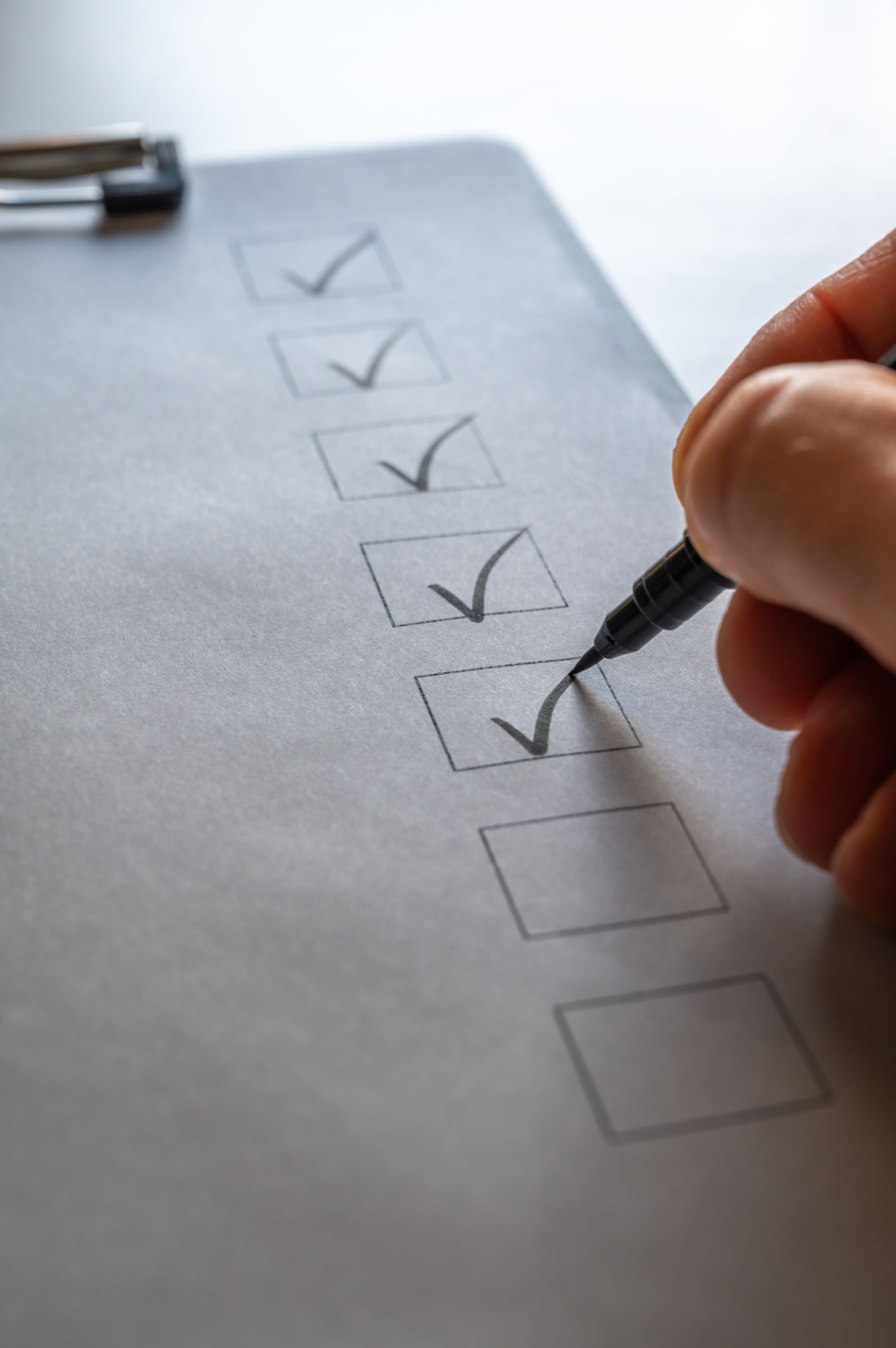 Checklist on a clipboard is checked off with black writing pen Checklist on a clipboard is checked off with black writing pen