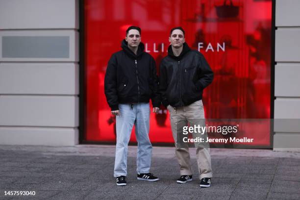 Alex Bönisch and Tobi Bönisch seen wearing a black sweater, black bomber jacket, blue wide jeans trousers, beige wide trousers and Adidas gazelle...