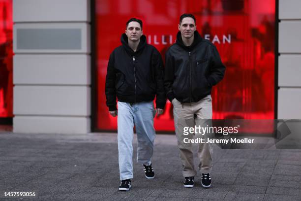 Alex Bönisch and Tobi Bönisch seen wearing a black sweater, black bomber jacket, blue wide jeans trousers, beige wide trousers and Adidas gazelle...