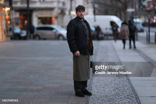 Noah Kächelin seen wearing Adidas gazelle sneaker, black leather jacket, black bomber jacket, green long coat, black trousers and a small black bag...