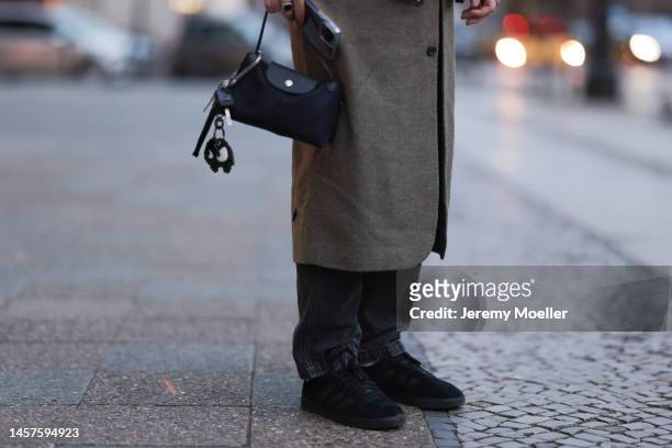 Noah Kächelin seen wearing Adidas gazelle sneaker, bblack bomber jacket, green long coat, black trousers and a small black bag before the William Fan...
