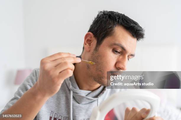 man applying serum to his shed beard - bristle stock pictures, royalty-free photos & images