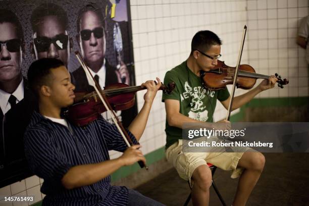 Two musicians play classical music on their violins May 31, 2012 on a subway platform in New York City. In 2011, New York's subway system delivered...