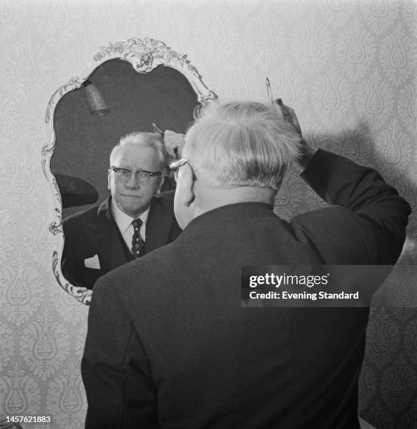 British politician Lord Herbert Morrison combing his hair in front of a mirror inside his new house in Eltham, London, on October 26th, 1960.