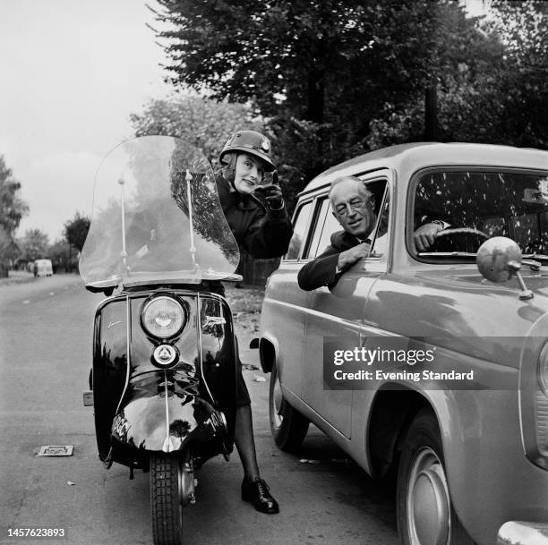 Female police officer of the Metropolitan Police Women's Highway Patrol on a scooter, giving advice to a driver in his car on October 26th, 1960.