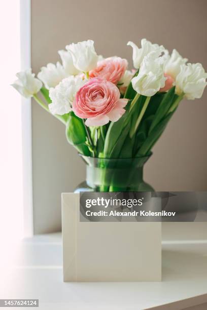 vase with spring flowers tulips, cloves and buttercups and empty card blank for text in home interior. mother's day. 8 march and easter concept - ranunculus bildbanksfoton och bilder