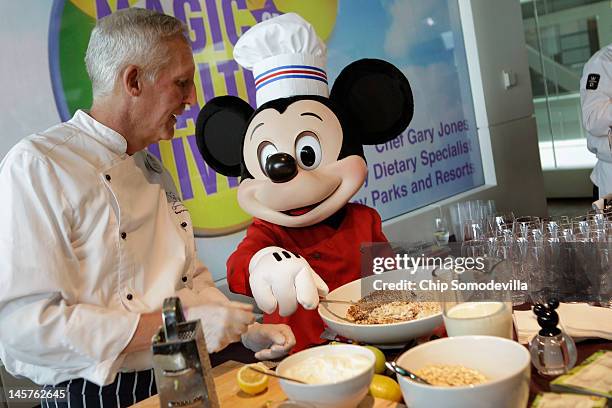 Mickey Mouse character assists Walt Disney Parks and Resorts Culinary Dietary Specialist Gary Jones make healthy smoothies during an event...