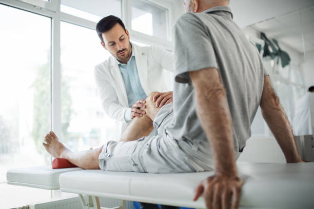 senior man having his knee examined by a doctor. - arthritis treatment stock pictures, royalty-free photos & images