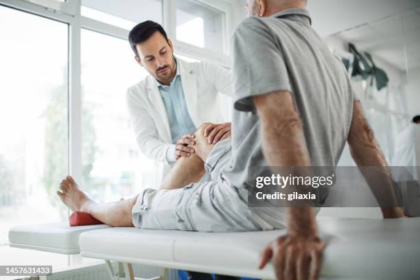 senior man having his knee examined by a doctor. - pain imagens e fotografias de stock