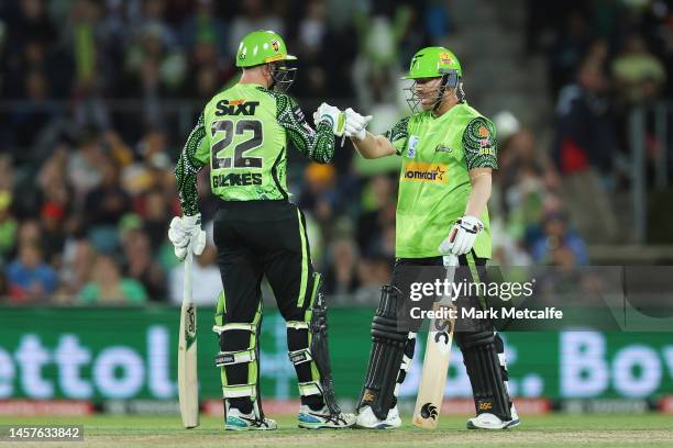 David Warner of the Thunder fist bumps Matthew Gilkes of the Thunder after hitting a six during the Men's Big Bash League match between the Sydney...