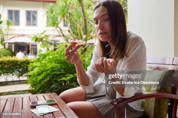 serious woman smokes cannabis with glass pipe sitting at table - green lighter stock pictures, royalty-free photos & images