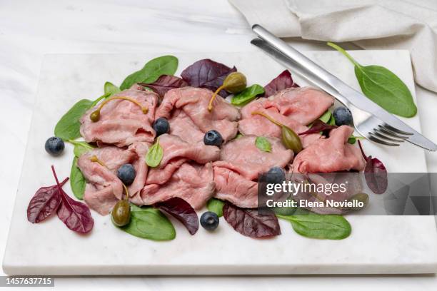 roast beef appetizer with spinach leaves capers and blueberries on a marble board - roast beef dinner stock pictures, royalty-free photos & images