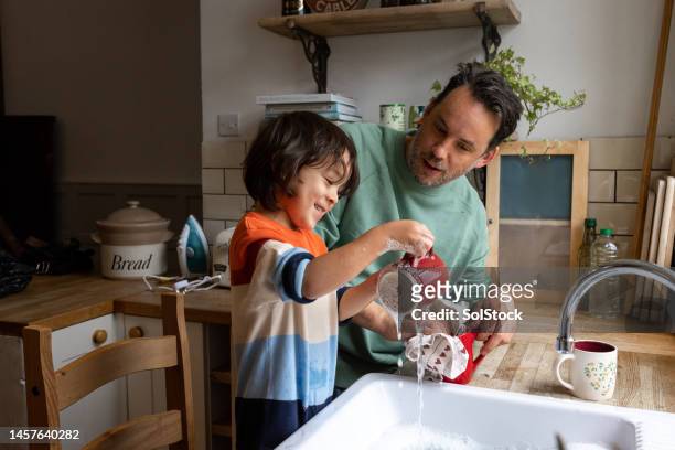 moments together with son - washing dishes bildbanksfoton och bilder