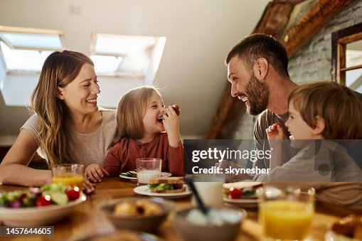 Junge Familie, die sich während des Frühstücks am Esstisch unterhält. Junge Familie, die sich während des Frühstücks am Esstisch unterhält.
