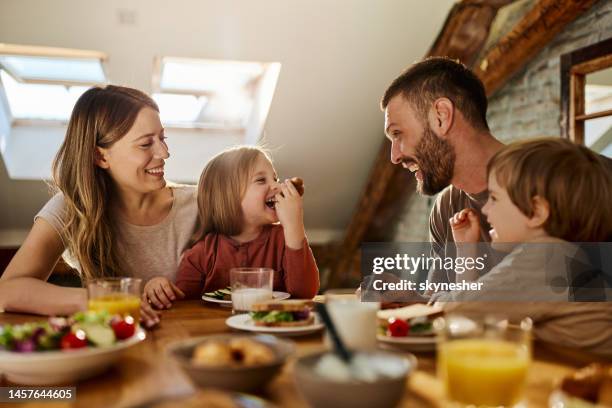 giovane famiglia che parla durante la colazione al tavolo da pranzo. - mangiare foto e immagini stock
