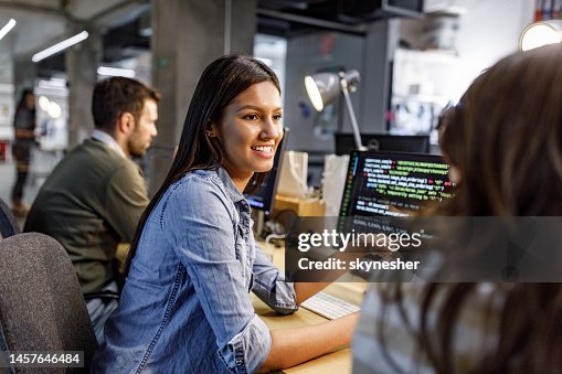 Happy female programmer talking to her colleague in the office. Happy female programmer talking to her colleague in the office.