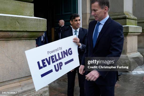 Prime Minister Rishi Sunak and Chancellor Jeremy Hunt fix a 'Powered By Levelling Up' sign on to Accrington Market Hall during a visit on January 19,...