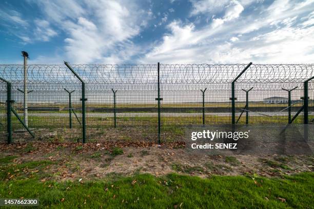 view of border separated by barbed wire against clear sky - prison fence stock pictures, royalty-free photos & images