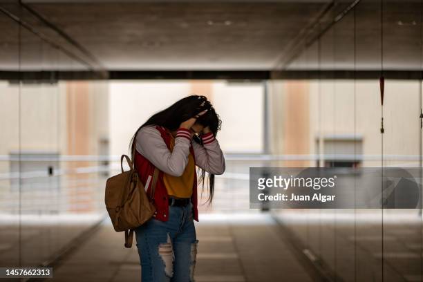 nervous female student touching head being bullied at school - girl sad stock-fotos und bilder