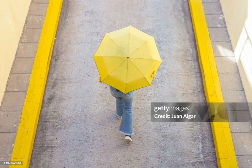 Unrecognizable woman walking under umbrella