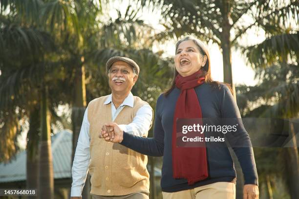 cheerful old couple holding hands at park - indian elderly couple stock pictures, royalty-free photos & images