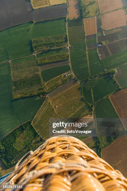 aerial photograph hot air balloon basket flying over farmland green fields - hot air balloon basket stock pictures, royalty-free photos & images