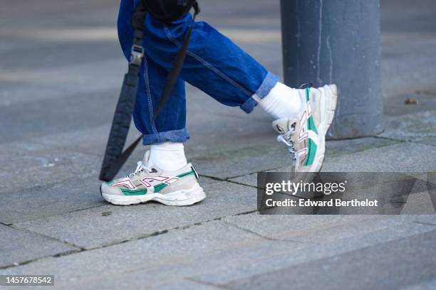 Guest wears blue denim large pants, white socks, beige leather and green suede sneakers , outside Lemaire, during Paris Fashion Week - Menswear...