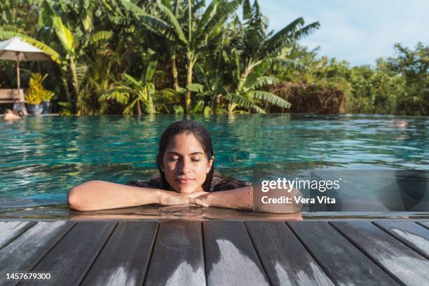 hispanic woman at hotel tropical resort sunbathing with palm trees in background - summer resort imagens e fotografias de stock