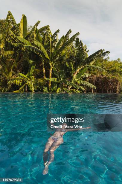 relax woman floating at tropical resort swiming pool with palm trees and turquoise water in background - villa vera hotel stock-fotos und bilder