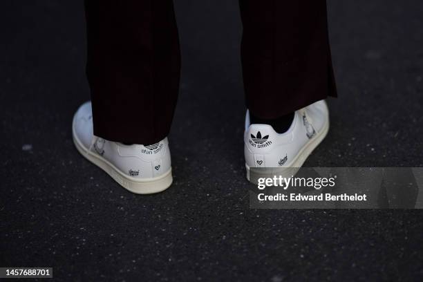 Guest wears black suit pants, black socks, white shiny leather with black painted Stan Smith sneakers from Adidas , outside Bianca Saunders, during...