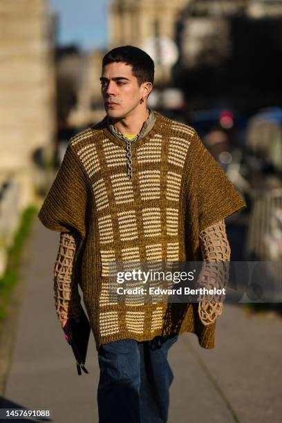 Guest wears gold earrings, a silver large chain necklace, a yellow t-shirt, a brown / beige braided wool oversized short sleeves / oversized t-shirt,...