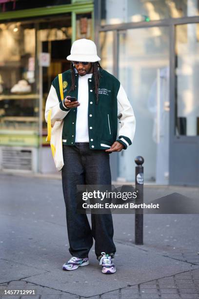 Guest wears a white fluffy bob hat, black sunglasses, a white t-shit, a dark green felt / wool with long white sleeves teddy coat, a white latte and...