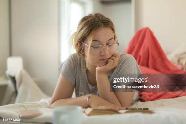a teenage girl is reading a book in bed in her room  with a cup of coffee on the table - coffee table reading mug stock pictures, royalty-free photos & images