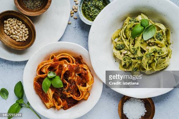 tomato pasta and pasta with basil pesto sauce, healthy vegan dish viewed from above - mediterranean food stock pictures, royalty-free photos & images