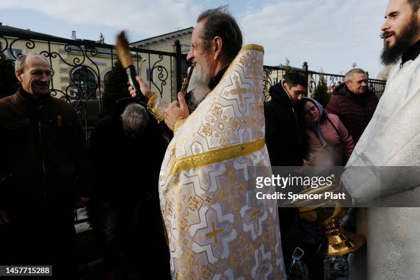 An orthodox priest splashes residents with water for the Orthodox holiday Epiphany, which commemorates the baptism of Jesus in the River Jordan in...