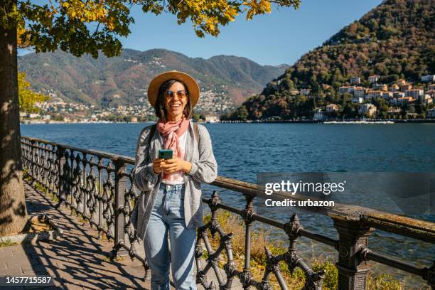 young woman using phone at lake como - como italia stock pictures, royalty-free photos & images