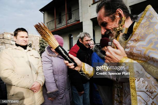 An orthodox priest splashes residents with water for the Orthodox holiday Epiphany, which commemorates the baptism of Jesus in the River Jordan in...