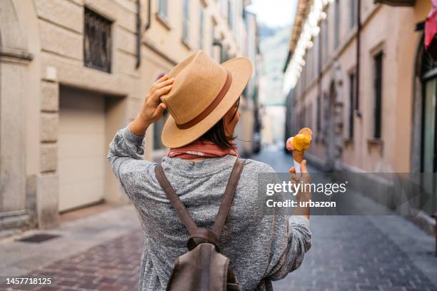 young woman eating ice cream on the street in como - como italia stock pictures, royalty-free photos & images