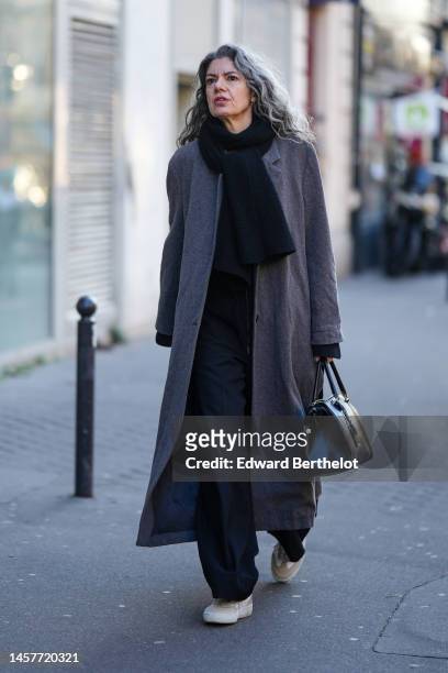 Guest wears a black wool scarf, a gray wool long coat, black large suit pants, a black shiny leather handbag, beige suede sneakers , outside Bianca...