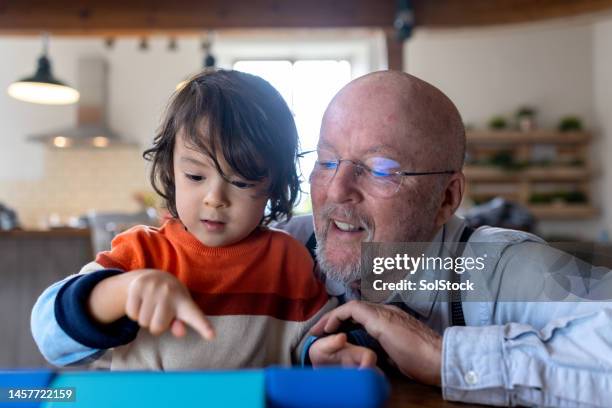 showing grandad something on digital tablet - long term stock pictures, royalty-free photos & images