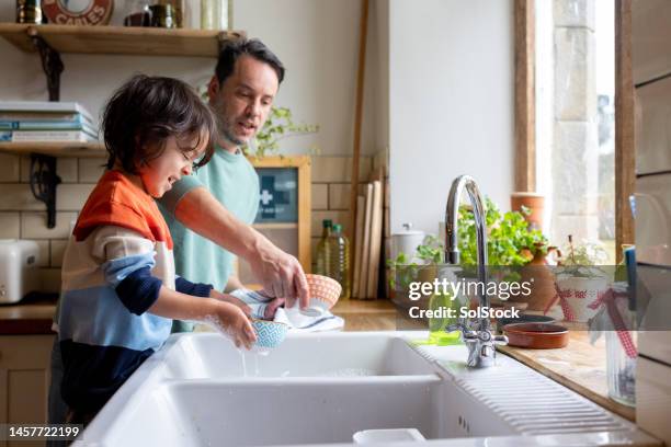 papa helfen, das geschirr zu reinigen - geschirr spülen stock-fotos und bilder