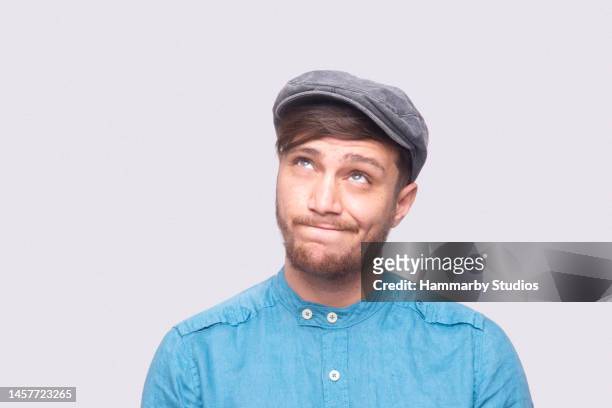 porträt eines jungen mannes, der denkt, indem er über grauen hintergrund aufschaut - man looking up beard chin stock-fotos und bilder